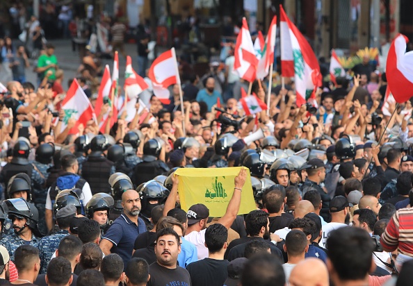 -Illustration des manifestations dans le monde, le Liban- Les forces de sécurité libanaises se tiennent entre partisans du mouvement chiite du Hezbollah et des manifestants antigouvernementaux sur la place Riad al-Solh à Beyrouth, le 25 octobre 2019, le neuvième jour de protestation contre les augmentations d'impôts et la corruption officielle. Photo by - / AFP via Getty Images.