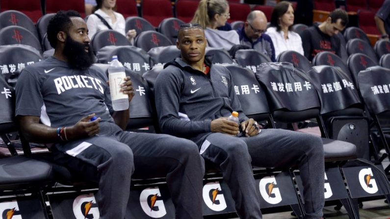 James Harden, n° 13 des Rockets de Houston, à gauche, et Russell Westbrook, n° 0, sont assis sur le banc pendant les échauffements avant de jouer un match d'avant-saison contre les Sharks de Shanghai au Toyota Center à Houston, Texas, le 30 septembre 2019. (Bob Levey/Getty Images) 