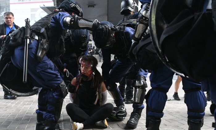 La police de Hong Kong détient une femme (assise au sol) près des bureaux du gouvernement central après que des milliers de personnes ont participé à une marche non autorisée à travers Hong Kong le 29 septembre 2019. (Mohd Rasfan/AFP via Getty Images)