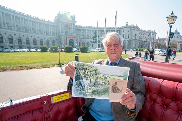 -Ulrich Habsburg-Lothringen, descendant de l'ancienne famille impériale d'Autriche-Hongrie, pose avec une copie d'un tableau de son grand-père Heinrich Ferdinand représentant un cimetière juif et une photo d'identité de Heinrich en uniforme militaire, devant le palais Hofburg à Vienne. Photo JOE KLAMAR / AFP via Getty Images.