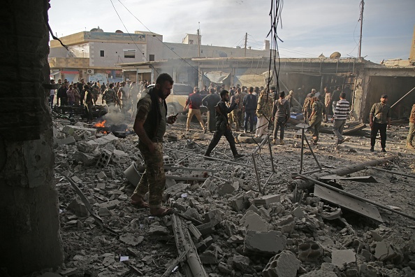 Des combattants syriens soutenus par la Turquie inspectent le site de l'explosion d'une voiture piégée dans la ville kurde syrienne du nord de la Syrie, Tal Abyad, à la frontière avec la Turquie, le 2 novembre 2019. (Photo :  BAKR ALKASEM/AFP via Getty Images)