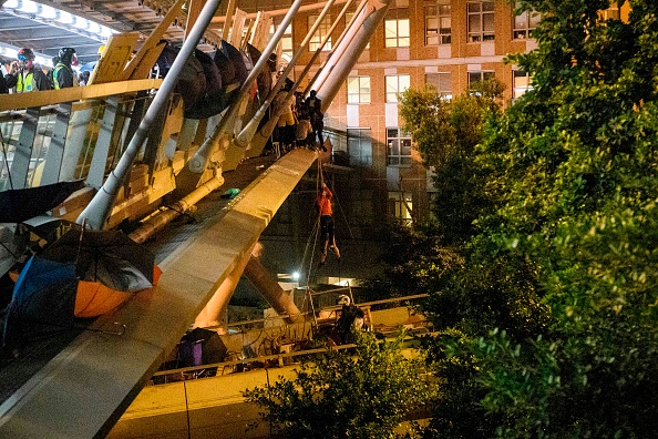 -Une manifestante glisse sur une corde pour s'évader du campus de l'Université polytechnique de Hong Kong et de la police dans à Hong Kong le 18 novembre 2019. Photo par ANTHONY WALLACE / AFP via Getty Images.