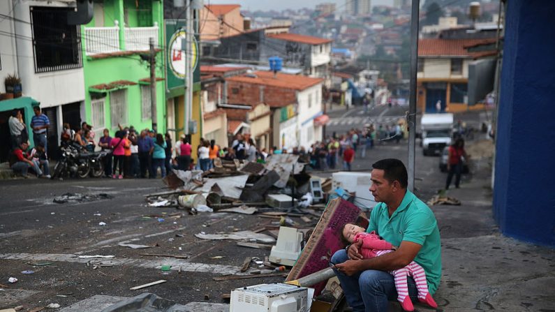 Un père et sa fille se reposent pendant que quelqu'un prend leur place avant l'aube dans une longue file d'attente pour acheter des aliments de base dans un supermarché le 8 mars 2014. (John Moore / Getty Images)