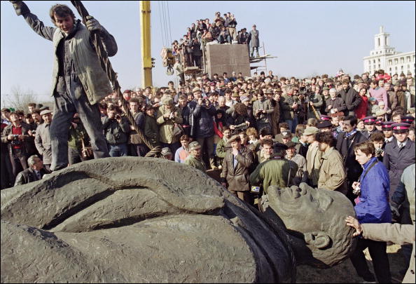 Un ouvrier roumain se dresse au sommet de la statue, sculptée dans un pur style de réalisme socialiste, du dirigeant révolutionnaire bolchevique russe Vladimir Ilitch Lénine après avoir été retirée de son piédestal le 5 mars 1990 à Bucarest ANDRE DURAND / AFP via Getty Images.