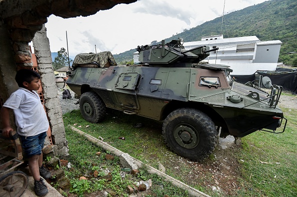 -Illustration- Un garçon regarde un véhicule blindé de l'armée colombienne à Toribio, dans le département de Cauca, en Colombie, le 30 octobre 2019. Cinq gardes autochtones ont été tués et six autres blessés mardi en Colombie lors d'une attaque, des groupes insurgés dissidents qui ont refusé de rejoindre l'accord de paix du pays. Photo de LUIS ROBAYO / AFP via Getty Images.