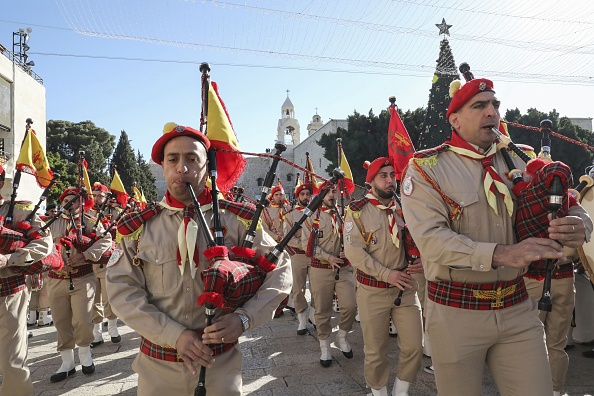 -Des éclaireurs palestiniens se produisent lors d'un défilé sur la place du Manger à l'extérieur de l'église de la Nativité dans la ville biblique de Bethléem, en Cisjordanie, le 24 décembre 2019 avant l'arrivée du patriarche latin de Jérusalem. Photo par HAZEM BADER / AFP via Getty Images.