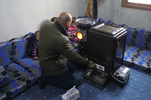 -Abu Walid réchauffe son salon avec un radiateur à pistache dans le village de Tal al-Karama, dans la province d'Idlib, dans le nord-ouest de la Syrie, le 6 décembre 2019. Photo par AAREF WATAD / AFP via Getty Images.