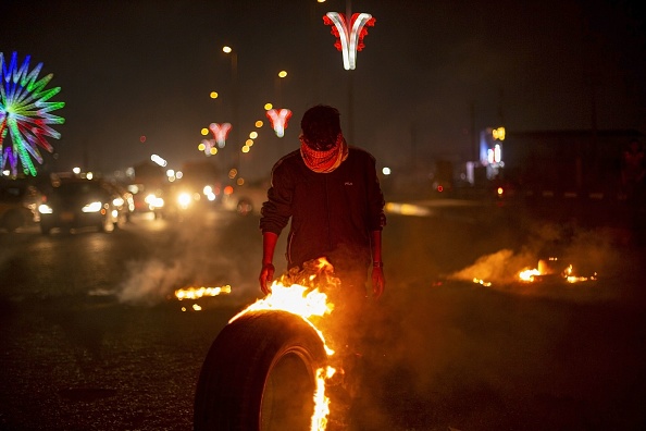 Un manifestant anti-gouvernement irakien fait rouler un pneu en feu à un barrage de fortune dans la ville de Bassorah, dans le sud du pays, le 26 décembre 2019. (Photo : HUSSEIN FALEH/AFP via Getty Images)