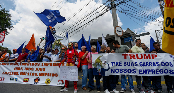 -Les membres des syndicats protestent contre la majoration à l'importation sur l'acier brésilien et la défense de leur emploi imposée par le président des États-Unis, Donal Trump, devant le consulat américain à Sao Paulo, au Brésil, le 5 mars 2018. Photo MIGUEL SCHINCARIOL / AFP via Getty Images.