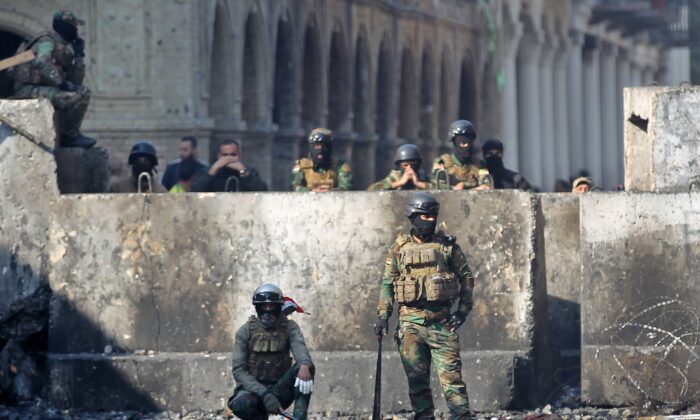 Les forces de sécurité irakiennes se rassemblent devant une barrière de béton sur la rue al-Rasheed à la capitale Bagdad, lors d'une accalmie dans les manifestations anti-gouvernementales, le 5 décembre 2019. (AHMAD AL-RUBAYE/AFP via Getty Images)