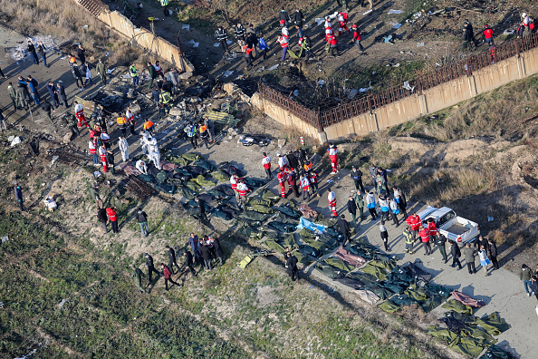 -Des personnes et des équipes de secours sont photographiées au milieu des corps et des débris d’un avion ukrainien transportant 176 passagers qui s'est écrasé près de l'aéroport Imam Khomeini dans la capitale iranienne, Téhéran, tôt le matin du 8 janvier 2020, tuant tout le monde à bord. Photo de ROUHOLLAH VAHDATI / ISNA / AFP via Getty Images.