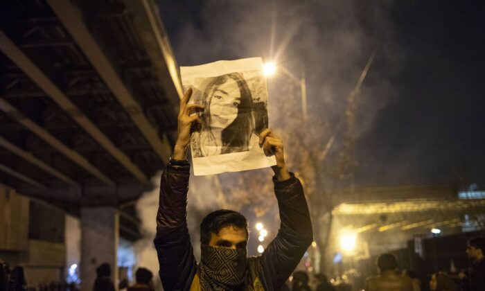 Un homme iranien tient la photo d'une victime de l'écrasement du vol 752 ukrainien lors d'une manifestation devant l'université Amir Kabir de Téhéran le 11 janvier 2020. (STR/AFP via Getty Images)