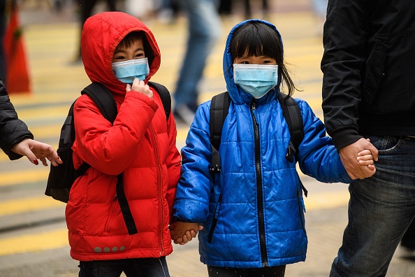 -Illustration- Des enfants portant des masques faciaux traversent une route lors d'un jour férié du Nouvel An lunaire du rat à Hong Kong le 27 janvier 2020. Photo par ANTHONY WALLACE / AFP via Getty Images.