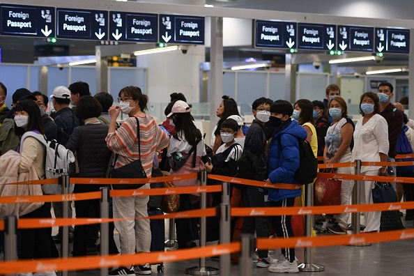 -Les touristes portant des masques faciaux font la queue au comptoir de l'immigration à leur arrivée à l'aéroport international le 29 janvier 2020. Les îles Mariannes du Pacifique interdisent les touristes chinois. Photo de MOHD RASFAN / AFP via Getty Images.