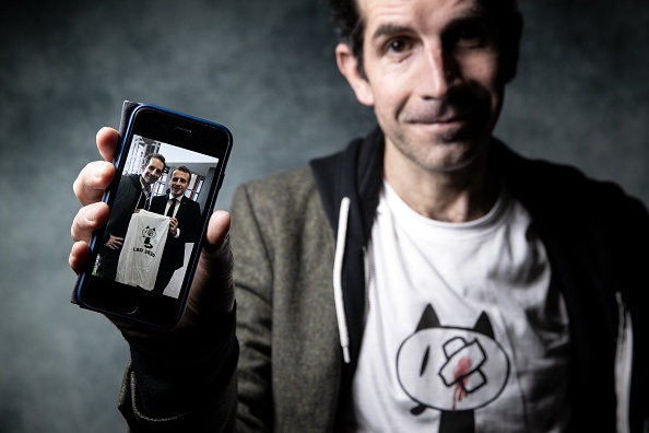 Le dessinateur de presse Julien Berjeaut, alias Jul, montre sur son smartphone une photo où il pose avec le président Emmanuel Macron, tenant un t-shirt que Jul a créé pour dénoncer les violences policières lors des récentes manifestations en France. La photo a été prise lors d'une séance photo au 47e Festival international de la bande dessinée d'Angoulême, à Angoulême le 30 janvier 2020.
(Photo : JOEL SAGET/AFP via Getty Images)