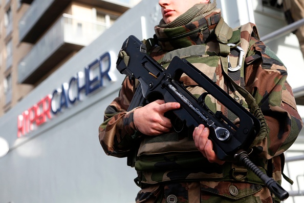 Un soldat monte la garde lors de la pose d'une plaque commémorative sur le supermarché juif Hyper Cacher à Paris, le 4 janvier 2016, à la mémoire de quatre personnes tuées lors d'une prise d'otages dans le magasin le 9 janvier 2015.  (Photo : THOMAS SAMSON/AFP via Getty Images)