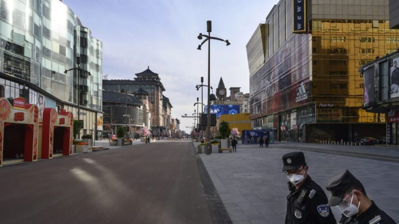 Deux agents de sécurité chinois surveillent une rue commerciale presque vide dans l'un des quartiers les plus animés de Wangfujing à Pékin, en Chine, le 18 février 2020. (Kevin Frayer/Getty Images)