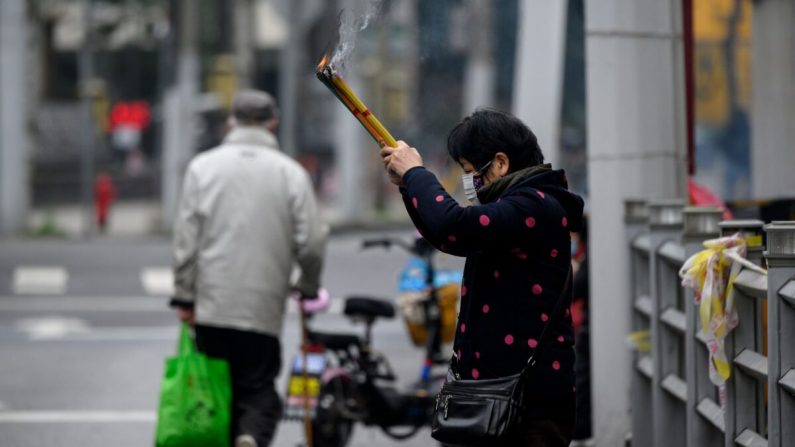 Une femme en prière devant le temple fermé du Bouddha de Jade à Shanghai, le 14 février 2020. (NOEL CELIS/AFP via Getty Images)