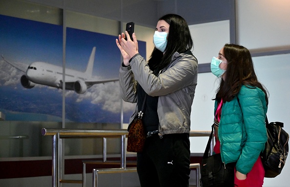 -Des touristes ukrainiens prennent des photos dans le hall d'arrivée de l'aéroport international Boryspil à l'extérieur de Kiev après le débarquement de leur avion de Chine le 30 janvier 2020. La réduction des vols internes et de certains vols internationaux aura une incidence sur les marchés du pétrole. Photo de Sergei SUPINSKY / AFP via Getty Images.