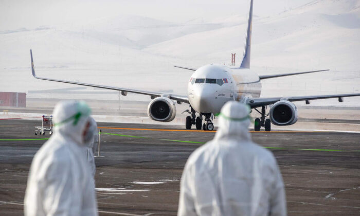 Des membres du personnel, portant des combinaisons de protection, observent un avion qui arrive à Oulan-Bator, capitale de la Mongolie, avec 32 citoyens mongols évacués de la ville chinoise de Wuhan, le 1er février 2020. (Byambasuren Enbyamba-OChir/AFP via Getty Images)