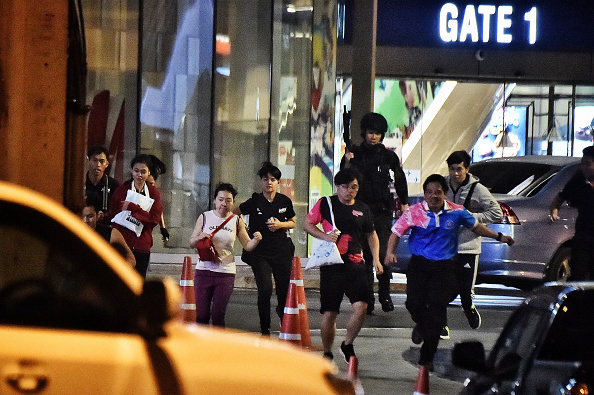 -Des gens courent ensemble alors qu'ils sont secourus par des commandos thaïlandais du centre commercial Terminal 21, où une fusillade a eu lieu, le 9 février 2020 dans la ville de Nakhon Ratchasima, dans le nord-est de la Thaïlande. Photo de Lillian SUWANRUMPHA / AFP via Getty Images.