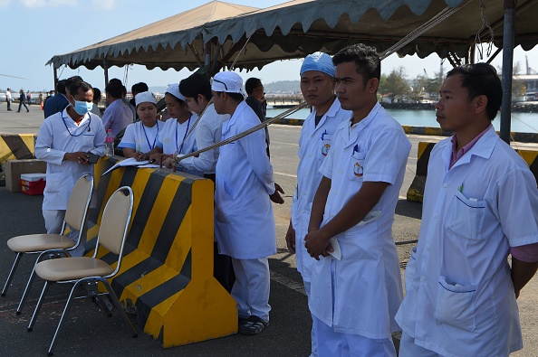 -Le personnel médical attend sur le quai alors que le navire de croisière Westerdam s'approche du port de Sihanoukville le 13 février 2020, où le paquebot a reçu l'autorisation d'accoster après avoir été refusé d'autres ports asiatiques en raison des craintes du coronavirus COVID-19. Photo de TANG CHHIN SOTHY / AFP via Getty Images.