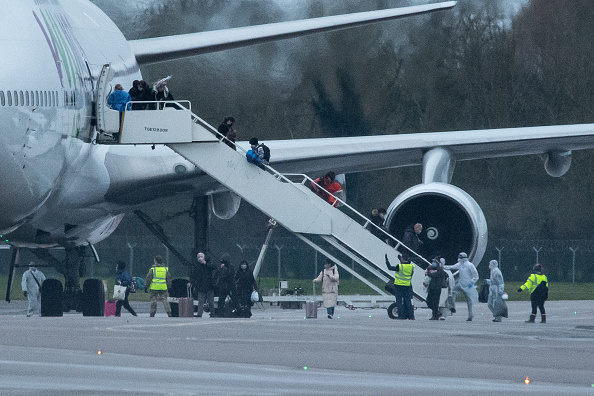 Des personnes en tenue de protection aident les passagers à descendre d'un avion, transportant 105 Britanniques et 95 ressortissants de pays européens qui ont été piégés à Wuhan en raison d'une épidémie de coronavirus, après avoir atterri à RAF Brize Norton en provenance de Chine le 9 février 2020 à Brize Norton, en Angleterre. (Photo : Leon Neal/Getty Images)