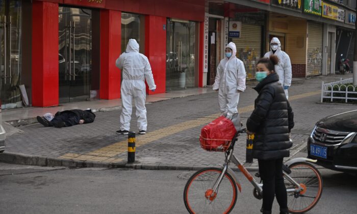 Un homme mort à terre dans une rue de Wuhan (Photo by Hector RETAMAL / AFP)