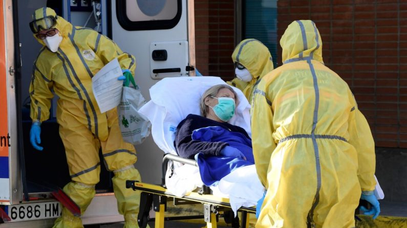 Des membres de la protection civile transportent un patient sur une civière à son arrivée à l'hôpital Severo Ochoa de Leganes, en Espagne, le 26 mars 2020. (Javier Soriano/AFP via Getty Images)