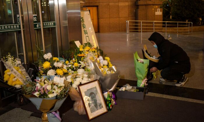 Un homme dépose des fleurs à côté d'une photo de feu l'ophtalmologue Li Wenliang devant l'hôpital central de Wuhan, en Chine, le 7 février 2020. (STR/AFP via Getty Images)