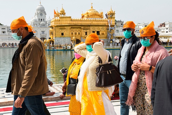 -Des dévots, portent des masques faciaux face à la propagation du nouveau coronavirus COVID-19, arrivent pour prier au Temple d'or d'Amritsar le 13 mars 2020. Photo de NARINDER NANU / AFP via Getty Images.