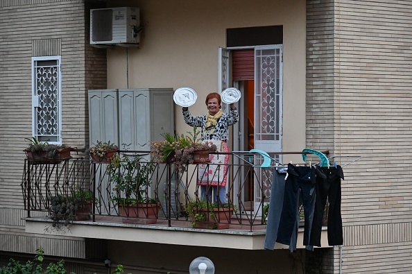 -Une résidente utilise des couvercles de casseroles pour jouer des cymbales alors qu'elle participe à un flash mob musical intitulé "Regardez par la fenêtre, la mienne de Rome!". Photo par ANDREAS SOLARO / AFP via Getty Images