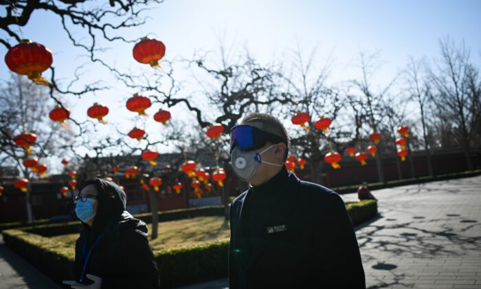 Un employé de parc avec des lunettes et un masque se promène dans un parc à Pékin, en Chine, le 14 mars 2020. (Wang Zhao/AFP via Getty Images)