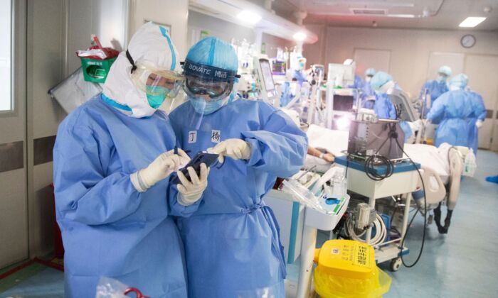 Le personnel médical utilise un téléphone portable alors qu'il traite des patients atteints du virus CCP dans un hôpital de Wuhan, en Chine, le 19 mars 2020. (STR/AFP via Getty Images)