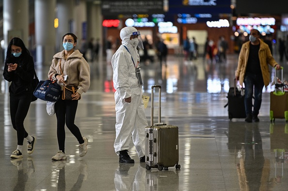 -Un membre du personnel de sécurité de l'aéroport porte un équipement de protection, au milieu des inquiétudes suscitées par l'épidémie de coronavirus de Wuhan, attend que les passagers les escortent vers un bus à l'aéroport international de Shanghai Pudong à Shanghai le 19 mars 2020. Photo par HECTOR RETAMAL / AFP via Getty Images.