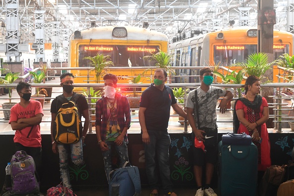 -Des passagers portant des masques attendent de monter à bord d'un train pendant un couvre-feu Janata (civil) d’une journée imposée à titre préventif contre le coronavirus COVID-19, dans une gare de Calcutta le 22 mars 2020. Photo de Dibyangshu SARKAR / AFP via Getty Images.