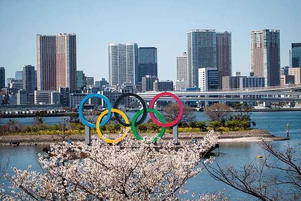 -Des cerisiers en fleurs sont vus près des anneaux olympiques dans le quartier d'Odaiba à Tokyo le 25 mars 2020, au lendemain de la décision historique de reporter les Jeux olympiques de Tokyo 2020. Le 25 mars, le Japon a commencé la tâche sans précédent de réorganiser les Jeux olympiques de Tokyo après la décision historique de reporter le plus grand événement sportif du monde en raison de la pandémie de coronavirus COVID-19 qui a enfermé un tiers de la planète. Photo de Behrouz MEHRI / AFP via Getty Images.