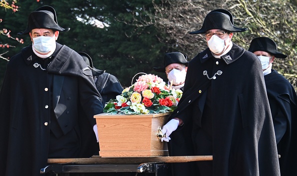 -Des membres de la fraternité caritative de Saint-Eloi de Béthune, avec chacun un masque facial, portent un cercueil vers une tombe, au cimetière de Pierrette à Béthune, le 27 mars 2020, alors que le pays est mis en quarantaine pour arrêter la propagation de la pandémie causée par le coronavirus venue de Wuhan. Photo par DENIS CHARLET / AFP via Getty Images.