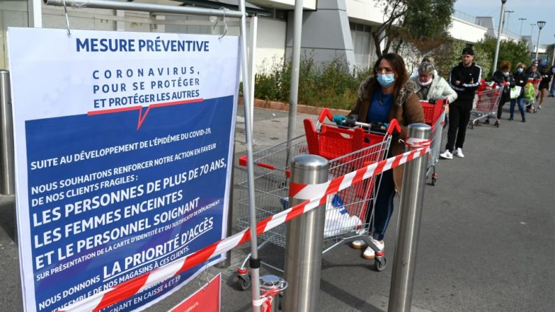 Des acheteurs observent la distanciation sociale alors qu'ils font la queue devant un supermarché de Montpellier, dans le sud de la France, le 30 mars 2020, au quatorzième jour d'un lockdown en France pour arrêter la propagation de l'épidémie COVID-19, causée par le nouveau coronavirus ou "virus du PCC".(Photo by PASCAL GUYOT/AFP via Getty Images)