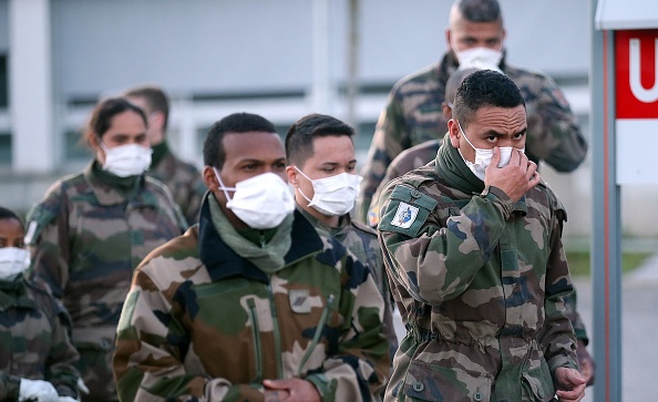 -Des soldats français portant des masques de protection arrivent pour installer des tentes dans le cadre d'un hôpital de campagne pour faire face à une flambée de cas du virus de Wuhan, le 22 mars 2020 à Mulhouse, en France. Photo de Johannes Simon / Getty Images.