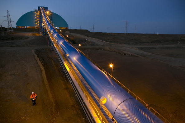 -Des travailleurs marchent le long de la bande transporteuse utilisée pour déplacer le minerai vers la zone de concentration de la mine Oyu Tolgoi le 10 octobre 2012 dans le désert du Gobi Sud, région de Khanbogd, Mongolie. Photo de Paula Bronstein / Getty Images;