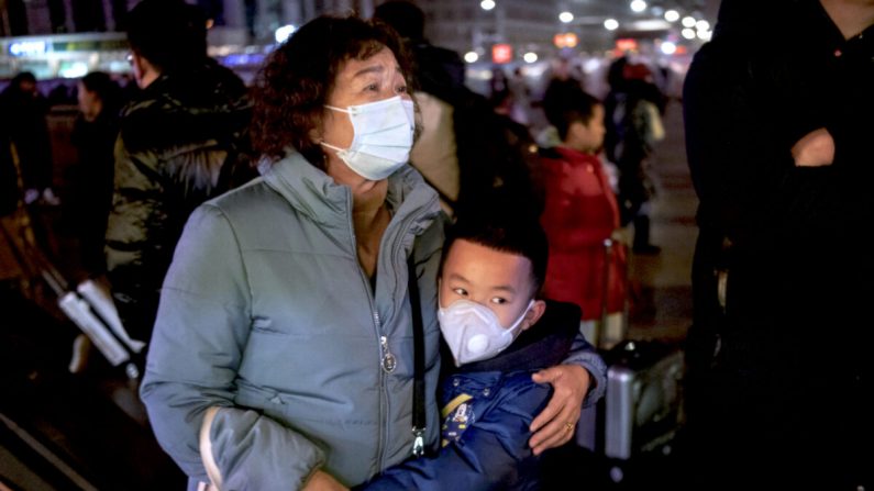 Un jeune garçon chinois enlace une parente alors qu'elle se prépare pour monter à bord d'un train à la gare de Pékin, en Chine, le 21 janvier 2020. (Kevin Frayer/Getty Images)