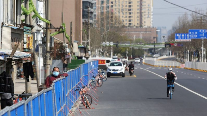 Un homme regarde par-dessus une barrière mise en place pour empêcher les gens d'entrer ou de sortir d'un complexe résidentiel à Wuhan, en Chine, le 17 mars 2020. (STR/AFP via Getty Images)