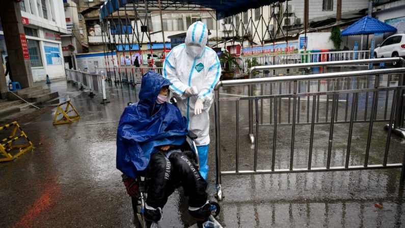 Le 27 mars 2020, un professionnel de la santé aide un homme qui demande un traitement dans la clinique de l'hôpital Huanggang Zhongxin à Huanggang, dans la province centrale du Hubei, en Chine. (Noel Celis/AFP via Getty Images)