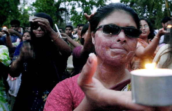 La victime d'une attaque à l'acide tient une bougie alors qu'elle participe avec d'autres à une cérémonie célébrant la Journée internationale de la femme à Dacca, le 7 mars 2005. Des milliers de femmes, d'organisations non gouvernementales et de groupes de défense des droits de l'homme participeront à diverses manifestations à travers le monde le 08 mars, pour marquer la journée. Photo FARJANA K. GODHULY / AFP via Getty Images.