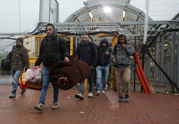 -Des ouvriers palestiniens entrent en Israël pour passer un point de contrôle entre la ville de Cisjordanie d'Hébron et Beersheva tout en portant des couvertures et des matelas le 18 mars 2020. Photo par HAZEM BADER / AFP via Getty Images.