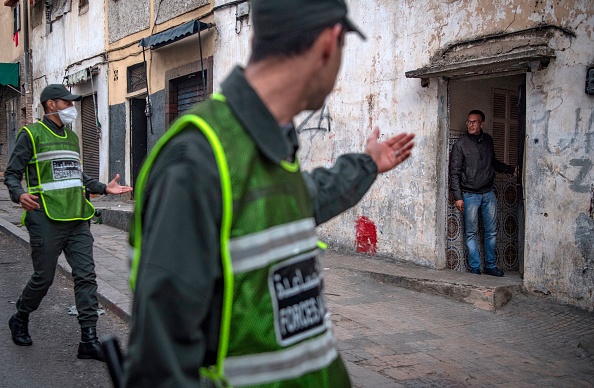 -Un membre des forces auxiliaires du ministère marocain de l'Intérieur, patrouillant dans le cadre d'une force de sécurité combinée plus importante, ordonne à un homme de rester chez lui comme mesure contre la pandémie dans le quartier de Takadoum, la capitale Rabat, le 27 mars 2020. Photo de FADEL SENNA / AFP via Getty Images.