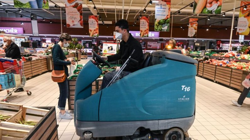 Un employé portant un masque facial et des gants de protection nettoie le sol avec une machine dans un supermarché de Montpellier, dans le sud de la France, le 30 mars 2020, au quatorzième jour d'un confinement en France pour arrêter la propagation de l'épidémie COVID-19, causée par le nouveau coronavirus. (Photo by PASCAL GUYOT/AFP via Getty Images)