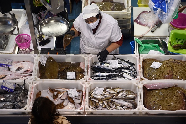 -Un poissonnier portant un masque facial sert un client dans un marché de Bueu, dans le nord-ouest de l'Espagne, le 2 avril 2020. Photo par MIGUEL RIOPA / AFP via Getty Images.