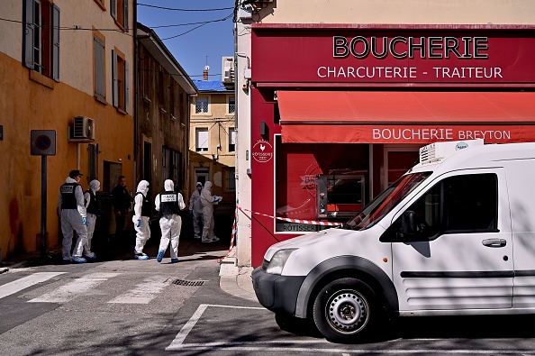 -Des officiers judiciaires de la police française en tenue de protection entrent dans une boutique du centre de Romans-sur-Isère, le 4 avril 2020, après qu'un homme a attaqué plusieurs personnes avec un couteau, tuant deux personnes et en blessant sept avant d'être arrêté ; Photo de JEFF PACHOUD / AFP via Getty Images.